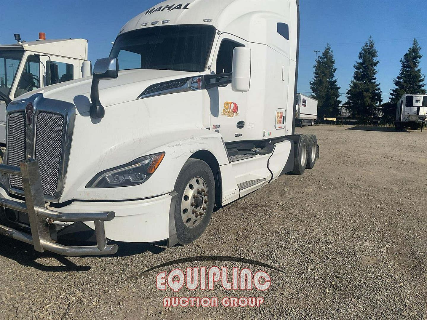 Kenworth T680 tractor-trailer in a gravel lot, white cab, front view with DEF/fluids area hidden