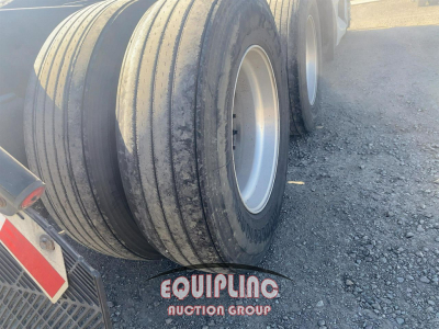 Trailer wheels and tires with Equipping Auction Group logo on the ground near wheel wells; no vehicle badge visible.