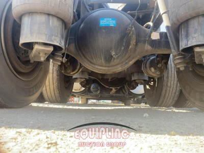 Kenworth T680 rear view showing rear axle, suspension, and mud flaps with a blue label on the differential cover; equipment in-service.