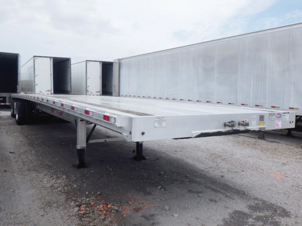 Aluminum flatbed trailer showing long deck and support legs with trailer hitch and side posts.
