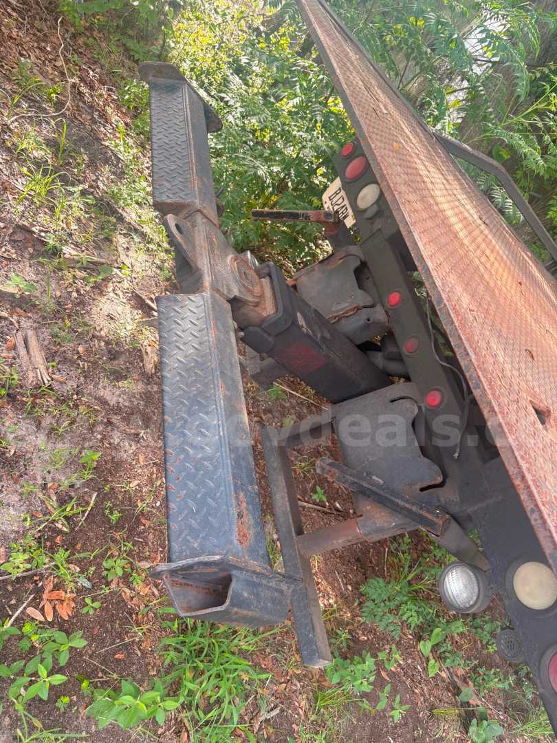 Freightliner FL80 tow truck chassis and hitch assembly showing bumper steps and hydraulic components