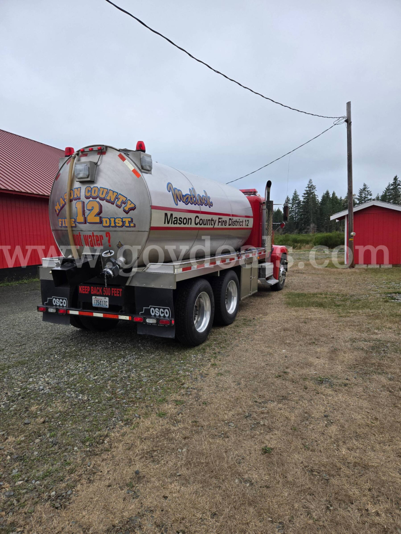 Semi-truck with a large cylindrical propane/tank trailer labeled by Mason County Fire Dept and water tank sign; rear view shows multiple wheels and bumper.
