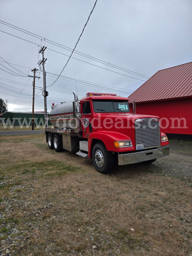 Truck front-left view of a red Freightliner FLD120 tanker truck with chrome bumper and cab, carrying a cylindrical tank.