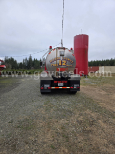 Tank trailer viewed from rear showing large cylindrical tank with red cap on right, bumper label ‘Keep Back 50 Feet’ and tanker rear with hazard markings. Freightliner-style trailer with water tank markings.