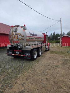 Semi-truck with a large cylindrical propane/tank trailer labeled by Mason County Fire Dept and water tank sign; rear view shows multiple wheels and bumper.