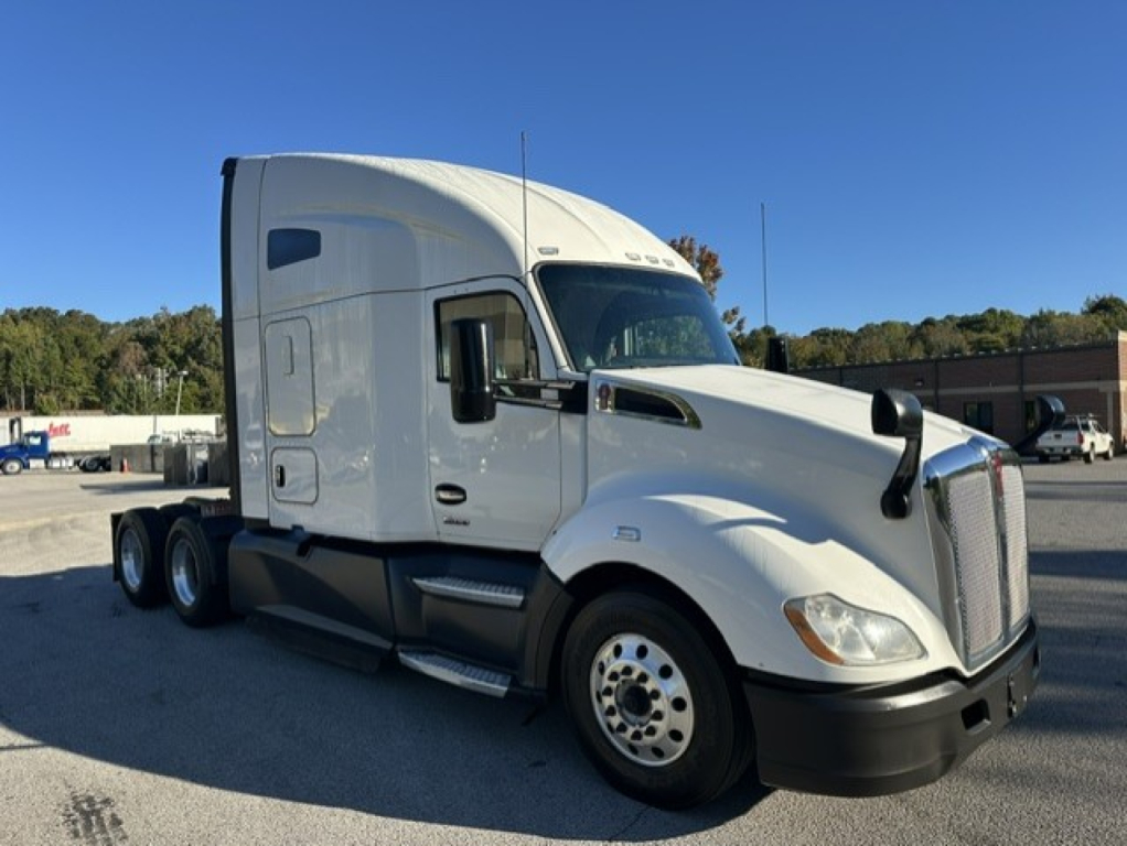 Kenworth T680 white sleeper cab tractor, front-left view, showing front grille, headlights, and dual rear axles.
