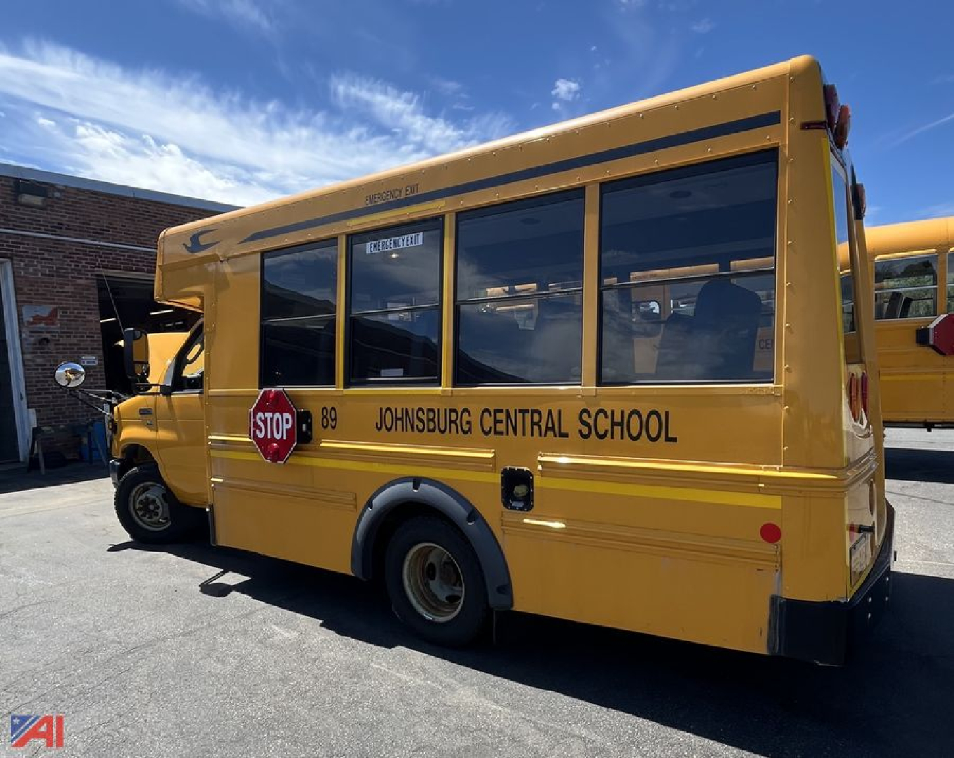 Ford Micro Bird cutaway school bus side view showing Johnsonburg Central School text, yellow body, stop sign, windows, wheel well, and rear badge.