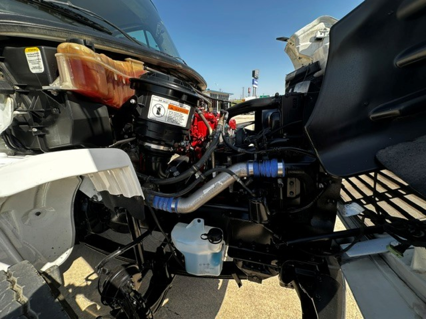 Freightliner M2106 engine bay showing exposed components, intake hoses, coolant reservoir, and various labels.