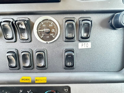 Dashboard control panel of a Freightliner truck showing gauges and switches. Visible text includes: a round gauge with numbers, various rocker switches labeled ENG FAN, OFF, ON, PTO, a small label 'PTO', and two yellow stickers reading 'WOR