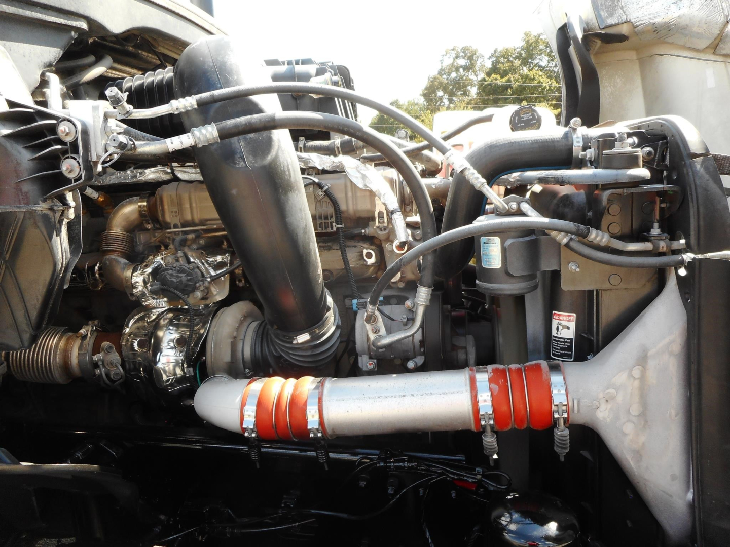 Freightliner diesel engine bay with intake piping and red silicone hoses visible.