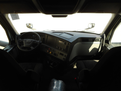 Truck cab interior showing steering wheel, dashboard, and instrument panel of a 2022 Freightliner Cascadia 126; visible vents, controls, and passenger seat.