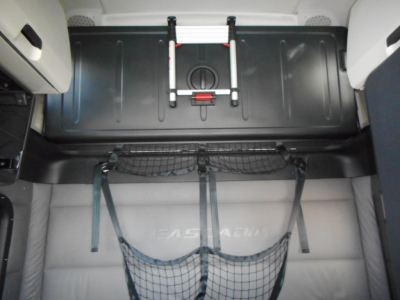 Truck interior cargo area of a 2022 Freightliner Cascadia 126 showing a storage bin, straps, and a net in the sleeper cab area.