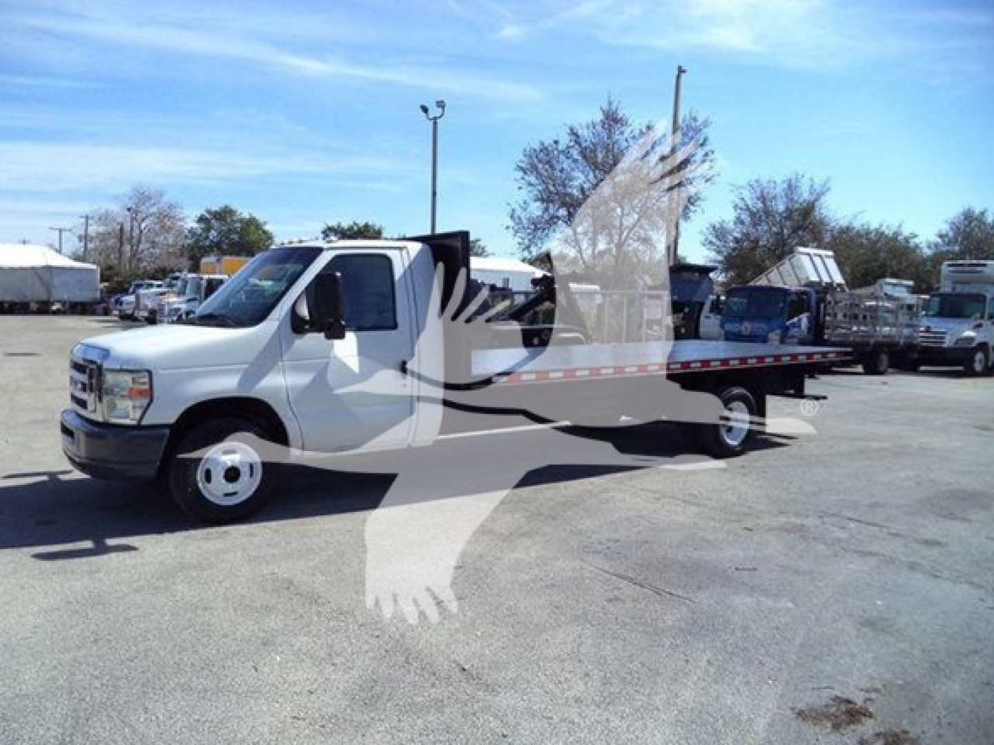 Ford E-450 flatbed tow truck with white cab and flatbed in a dealership lot, VIN 1FDXE4FS9BDA22070 visible in listing context.