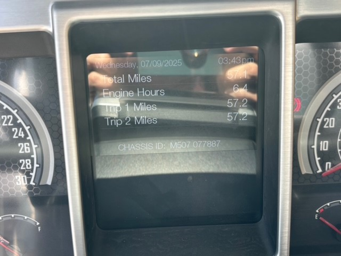 Mack MD7 dash display showing total miles, engine hours, and trip meters with chassis ID; center display with data readouts and surrounding gauges.