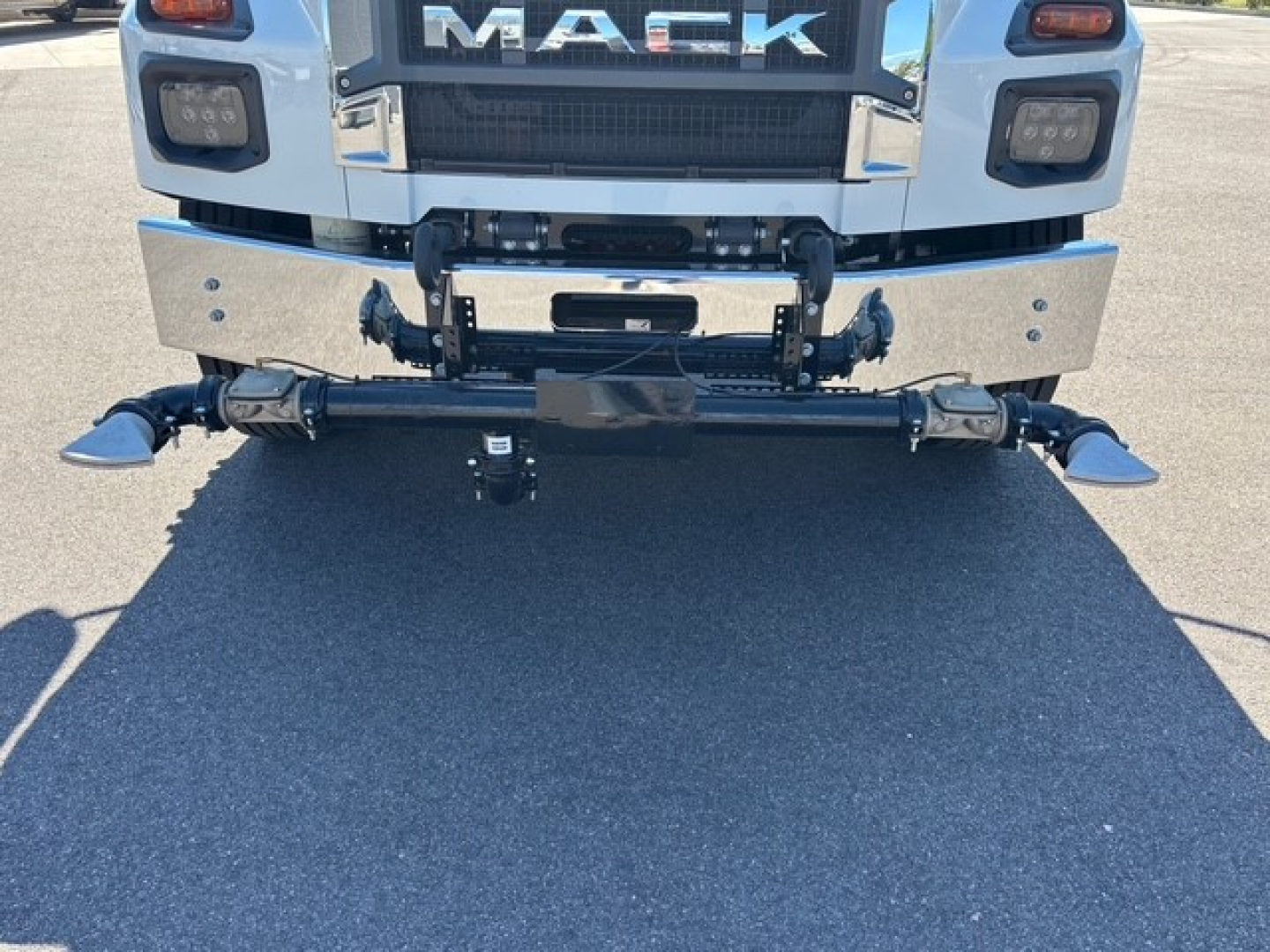 Mack MD7 truck front view showing bumper with chrome panels, central hitch assembly, and winch/loader hardware; visible 'MACK' badge on grille.