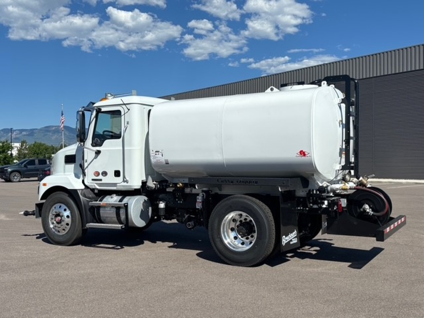 Mack MD7 vacuum/ liquid tanker truck side view showing cylindrical tank and rear hoses.
