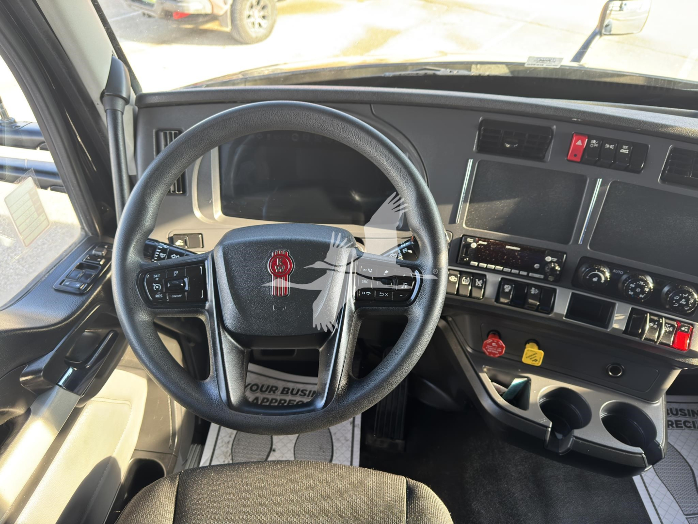 Kenworth T680 truck cockpit interior showing steering wheel, dashboard controls, and center console with gauges and switches.