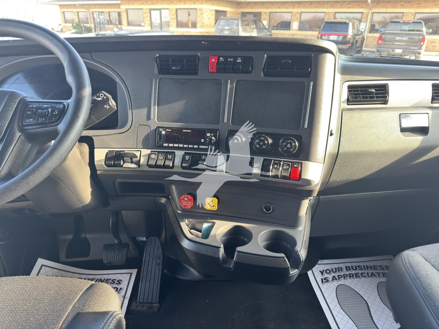 Kenworth T680 dash and center console showing driver's pedal area and dashboard controls.