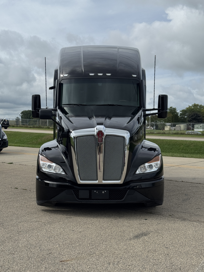 Front view of a black Kenworth T680 truck with large chrome grille, dual side mirrors, and aerodynamic hood.