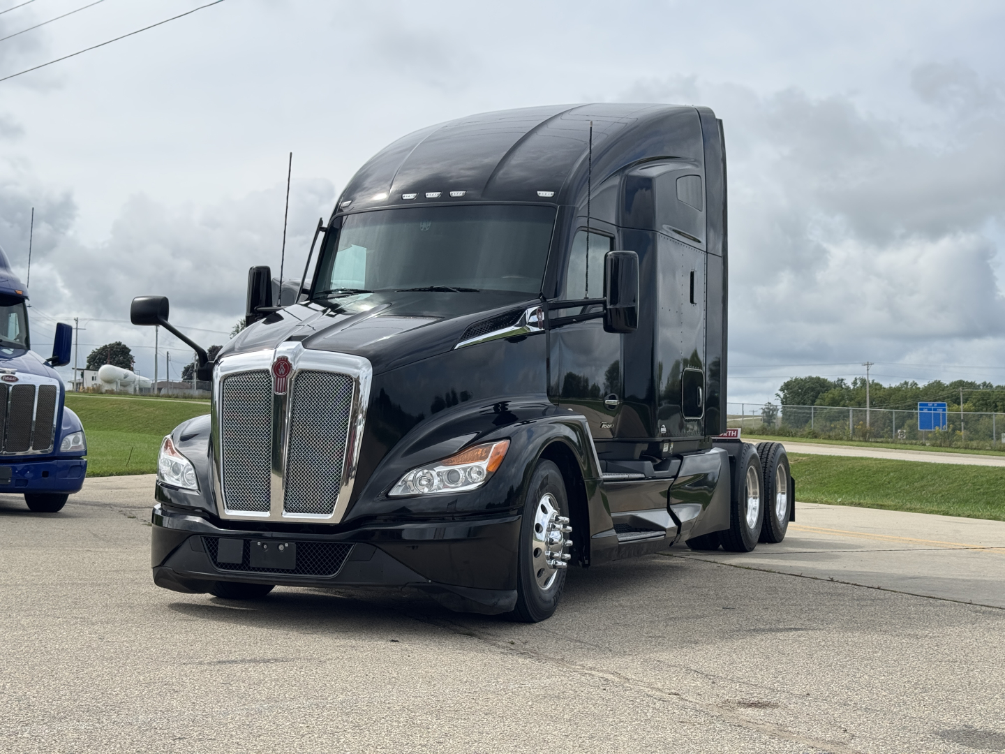 Kenworth T680 conventional sleeper truck in view showing front grille and cab with dual rear axles