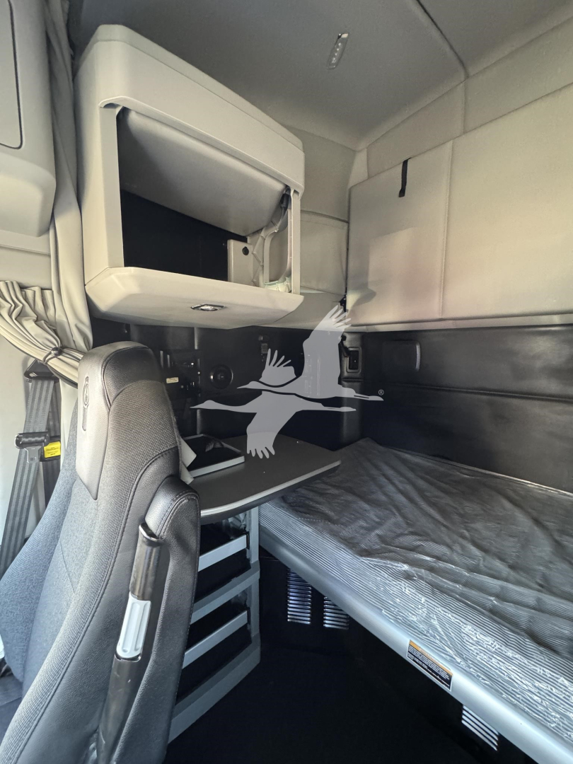 Kenworth T680 sleeper cab interior showing bunk bed area, storage cabinet, and desk with drawer unit.