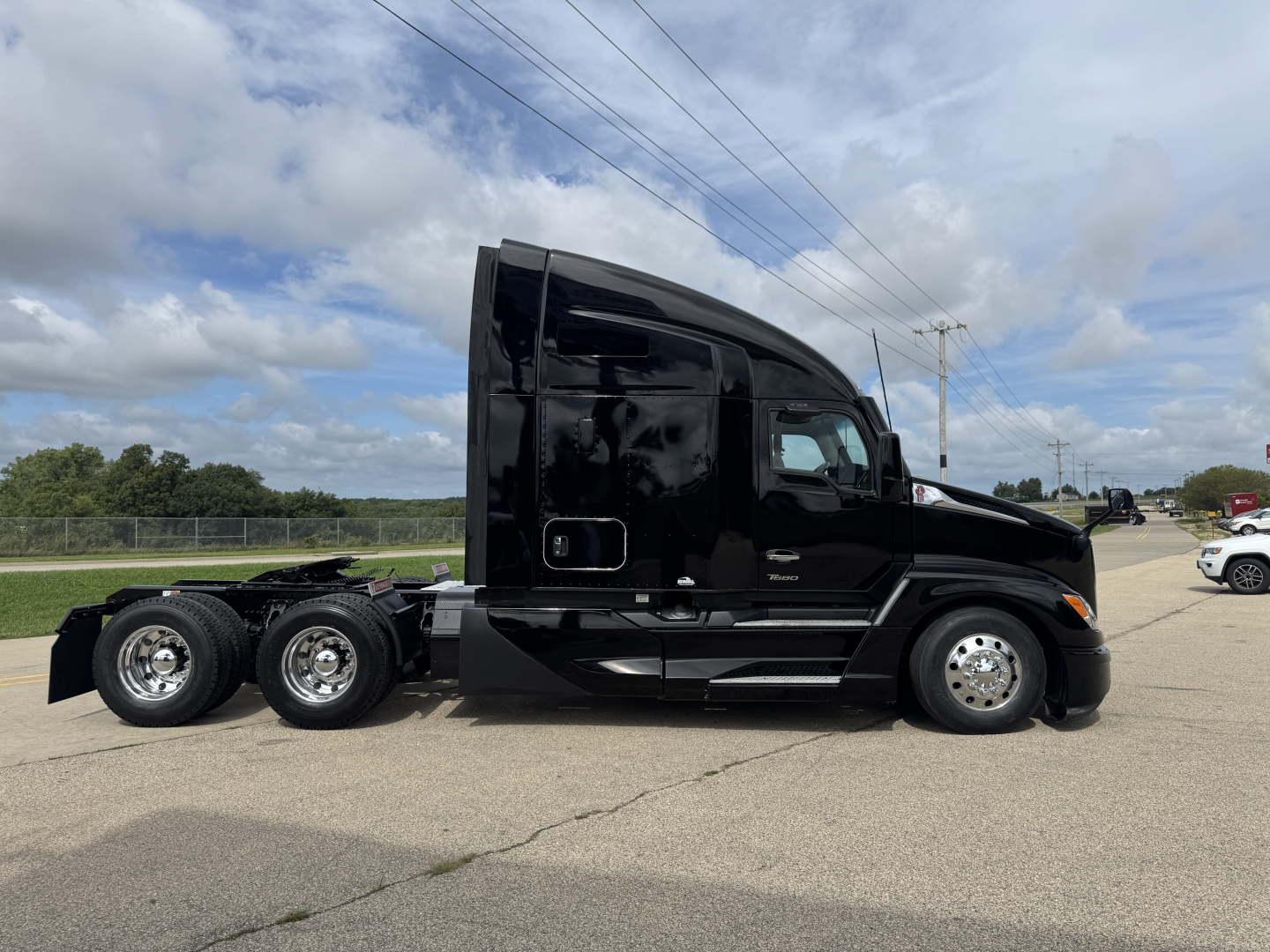 Kenworth T680 tractor in-service showing side view with two rear axles and glossy black paint. No legible labels visible.