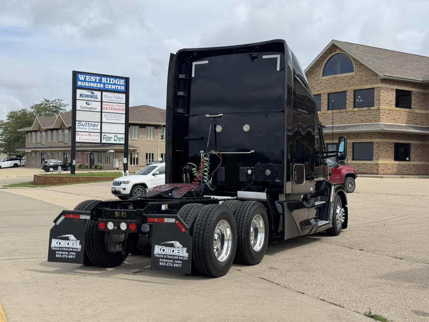 Kenworth T680 tractor, black, side and rear view with dual rear axles, mud flaps reading Kordell with phone numbers, rear black fifth wheel area, trailer connections visible.