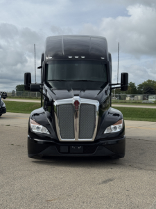 Front view of a black Kenworth T680 truck with large chrome grille, dual side mirrors, and aerodynamic hood.