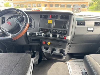 Kenworth T680 dashboard and steering wheel interior with center control panel, dual cup holders, and various switches visible.