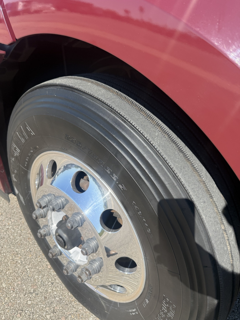 Wheel and tire close-up on Freightliner Cascadia 126 front left side showing hub, lug nuts, and tire tread.