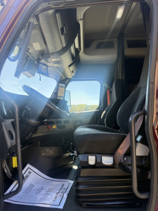 Cab interior of a 2021 Freightliner Cascadia126 tractor showing driver's seat, dashboard, and entry area.