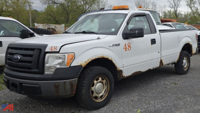 Front and side view of a white 2011 Ford F-150 pickup truck with orange 48 numbers on door and fender, rust along lower body, black front bumper, orange beacon on cab roof, two-tone wheels.
