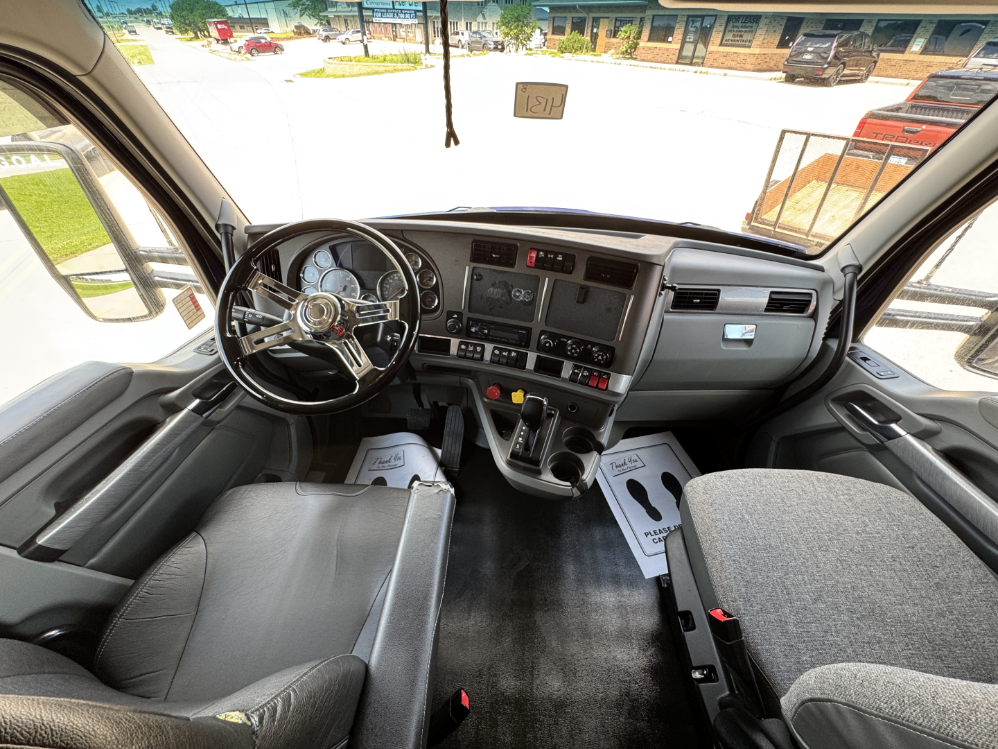 Kenworth T680 interior cockpit view showing steering wheel, dashboard, center console, and driver and passenger seats.