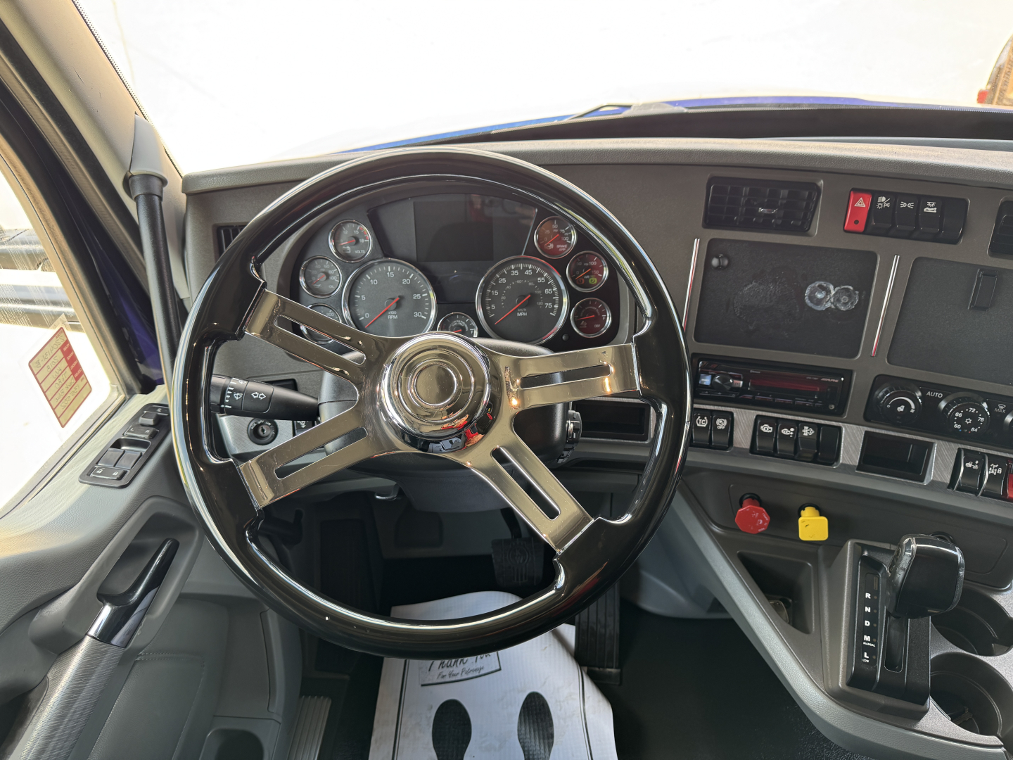 Kenworth T680 truck interior showing steering wheel, dashboard gauges, and center console with control switches.