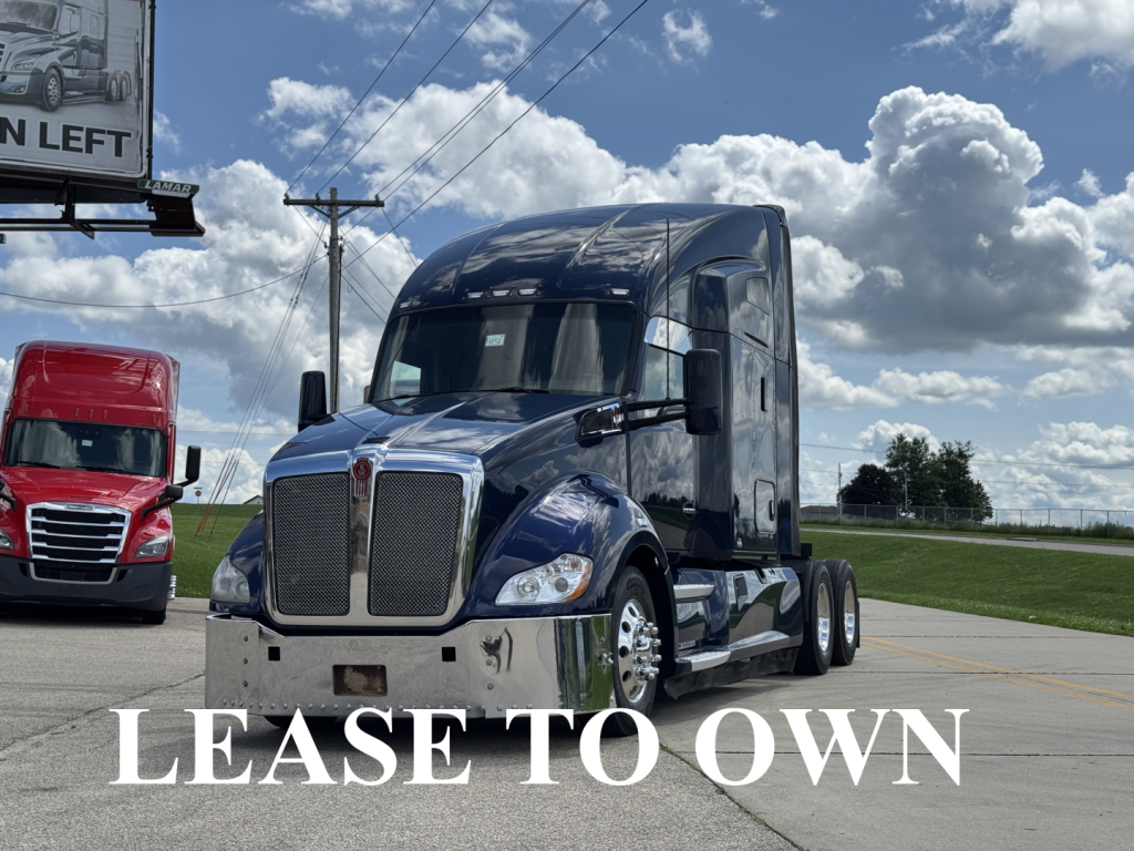 Kenworth T680 tractor-trailer in blue, front view, chrome grille and bumper, large windshield, power lines and a red truck in background.