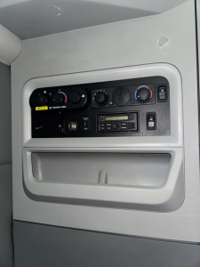 Kenworth T680 dash panel showing climate controls, radio, and storage pocket in the cab door area.
