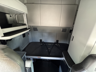 Kenworth T680 truck interior showing sleeper cab area with storage shelves and tie-down straps.