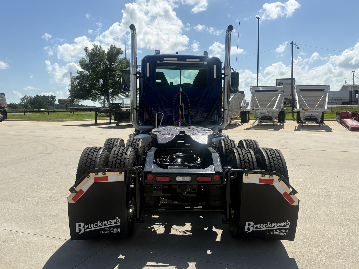Truck rear view showing fifth wheel hitch and dual rear axles with mud flaps labeled Bruckner’s, blue cab, daytime.