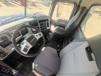 Mack PI64T truck cabin interior showing steering wheel, dashboard, driver seat, and passenger seat with center console.