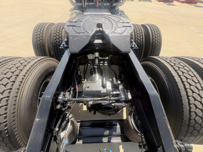 Truck chassis rear view showing drivetrain, suspension, and dual rear axles with tires.