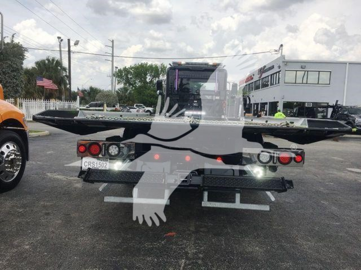 Back of a Peterbilt rollback truck trailer hitch platform with taillights and license plate CRS1502; a watermark of a bird-like logo overlays the image.