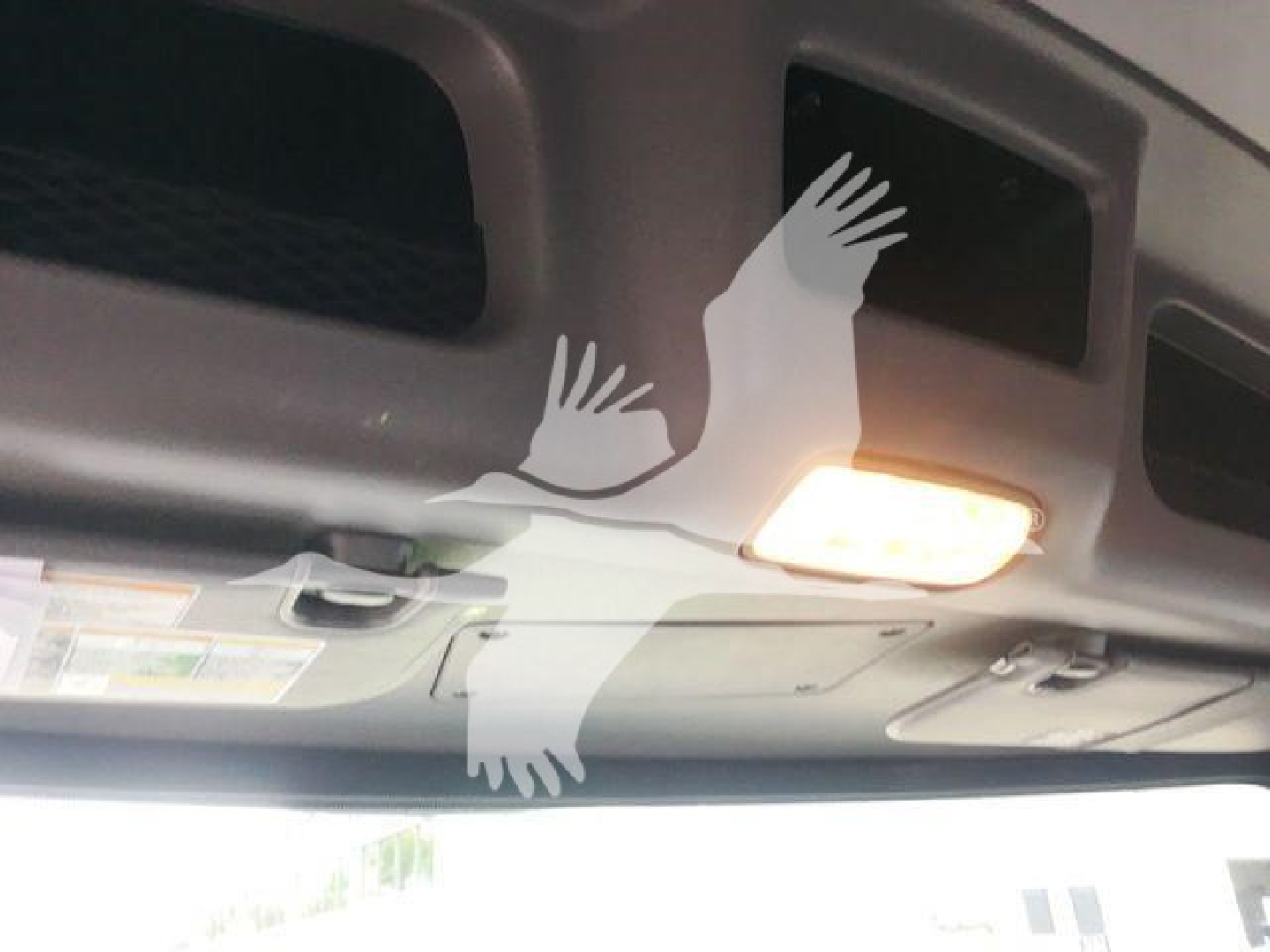 Interior view of a 2022 Peterbilt 337 dashboard area with overhead mirrors and a sun visor light; sticker labels are visible but unreadable due to angle.