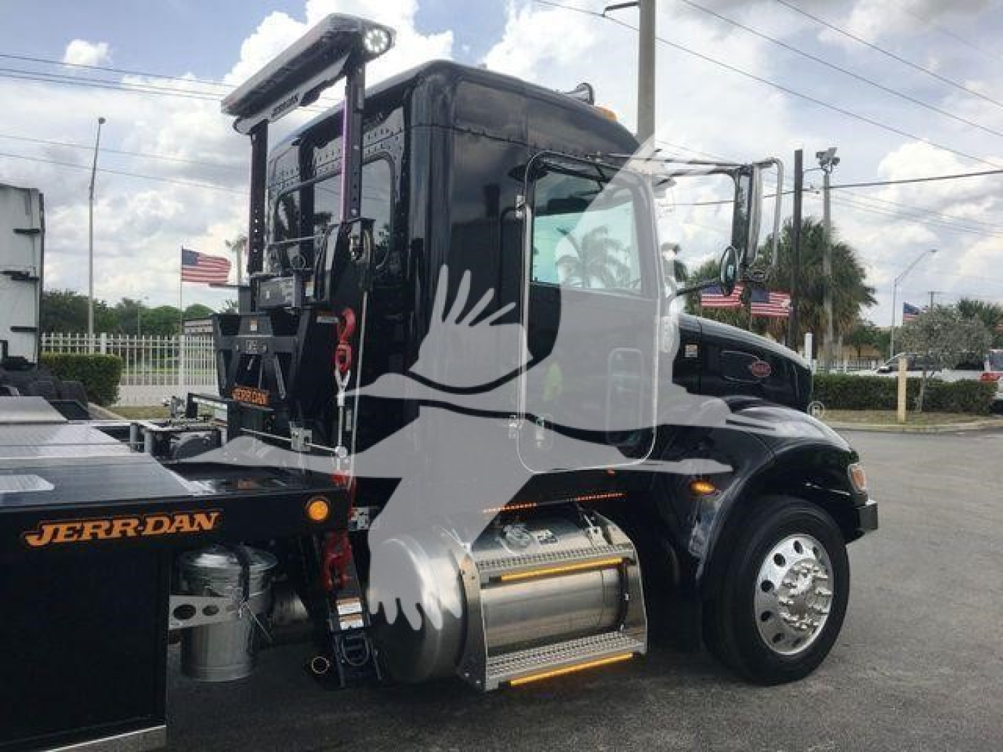 Peterbilt 337 cab with rollback equipment and chrome fuel tank in a dealership lot.