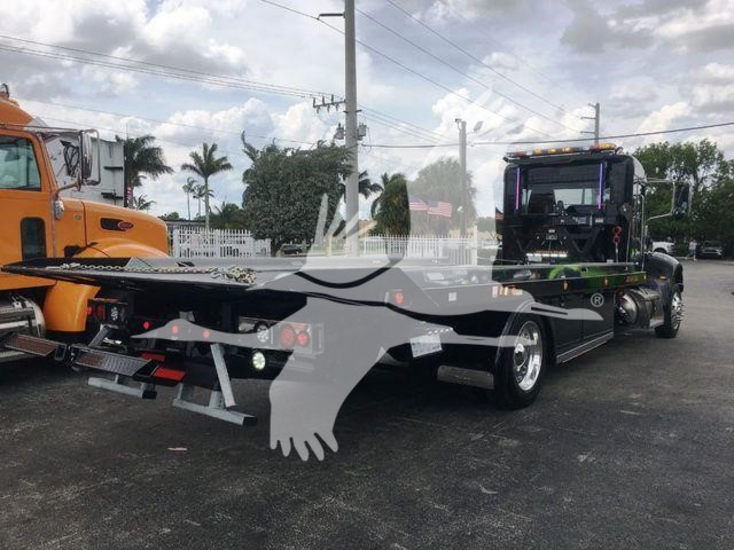 Peterbilt 337 rollback truck with a flatbed trailer, rear view showing dual rear axles and towing equipment, stock number STEPSIDE337SRS in background.