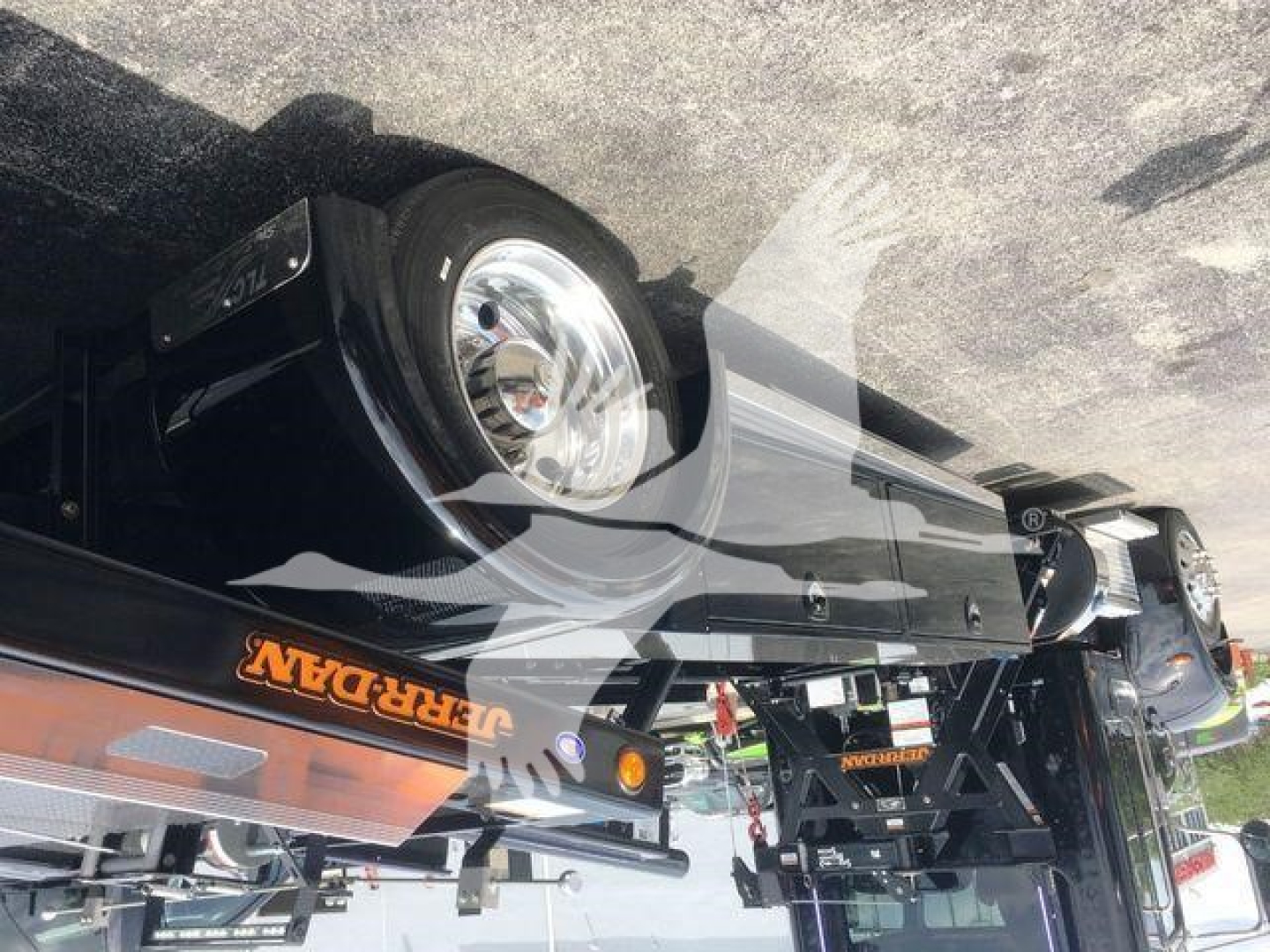 Peterbilt 337 rollback truck in-service with orange branding on side; front bumper and headlight visible; additional equipment and stabilizers present.