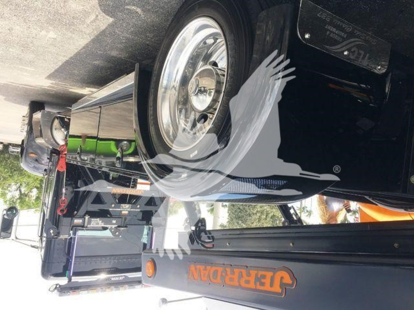 Peterbilt 337 rollback truck showing chrome wheel and side body with green accent; visible text on equipment includes 'Jerr-Dan' on the rollback arm and other generic truck components.