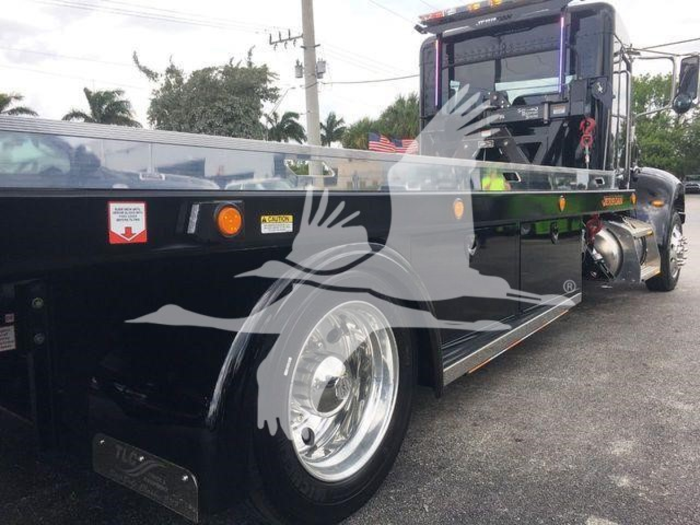 Peterbilt 337 rollback truck with a flatbed, side view showing front wheel and cab back detail.
