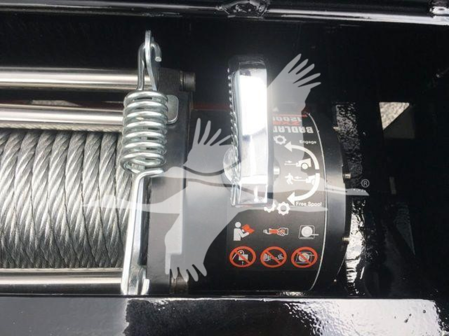 Winch winch cable drum with warning icons and labels on black housing. Visible text includes icons and symbols on the drum, no clear model-specific text readable.