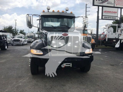 Front view of a white 2022 Peterbilt 337 rollback truck with black fenders, chrome grille, dual mirrors, and towing hook visible; stock number STEPSIDE337SRS in a dealership lot.