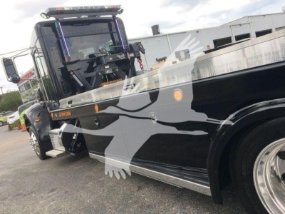 Peterbilt 337 rollback truck showing side profile with graphic design and crane area.